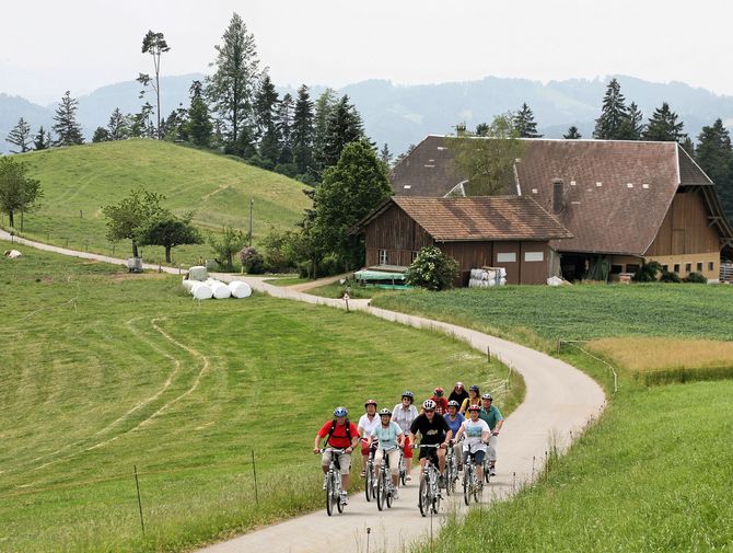 Eine Velogruppe fährt auf ihrem Weg von Willisau nach Burgdorf an einem Bauernhof vorbei.