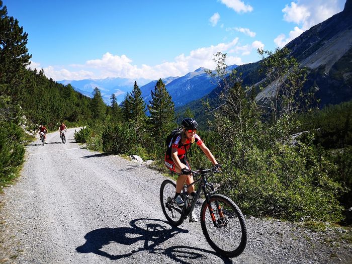Drei Mountainbiker fahren auf einem Kiesweg im Schweizer Nationalpark.