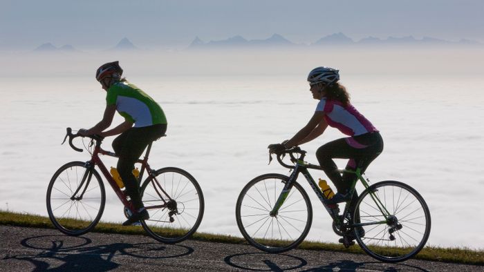 Zwei Radfahrer auf dem Chasseral mit Nebel im Hintergrund.