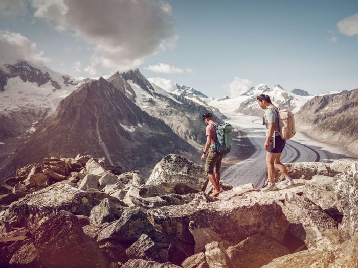 Ein Paar befindet sich auf dem Aletsch Panoramaweg direkt vor dem Aletschgletscher.